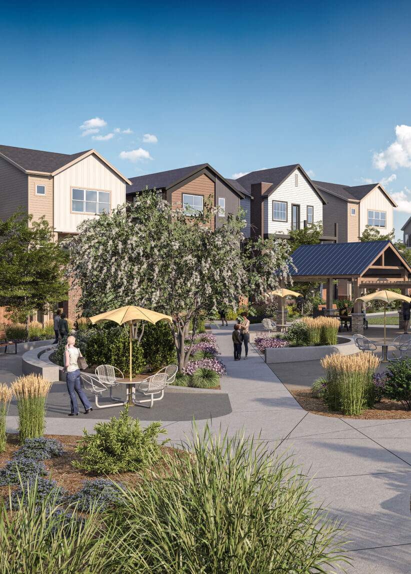 A landscaped residential courtyard at Uplands Westminster features trees, benches, and outdoor seating under umbrellas, with people walking or relaxing under a blue sky—discover beautiful homes for sale in Westminster CO.