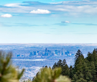 A distant city skyline is visible under a blue sky, framed by trees and greenery in the foreground—an inviting view near sought-after Uplands Westminster homes for sale.