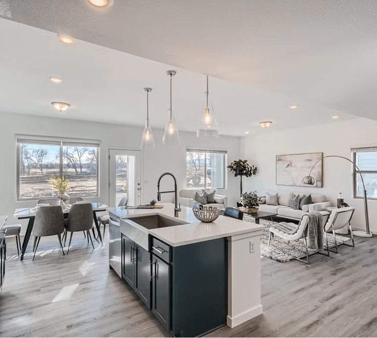 Open-concept living space in Uplands Westminster with a modern kitchen island, dining area, and a bright living room featuring large windows and contemporary furnishings—discover Uplands Westminster homes for sale today!.
